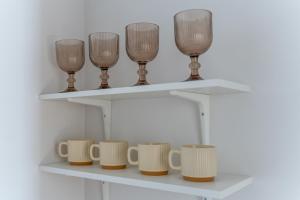 a shelf with four wine glasses and cups on it at Spacious Studio Near Station Klaipėda in Klaipėda