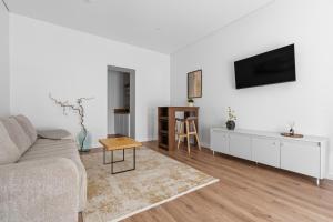 a living room with a couch and a tv on a wall at Spacious Studio Near Station Klaipėda in Klaipėda