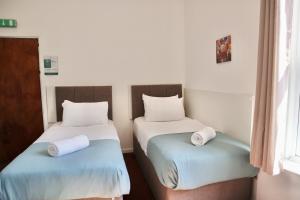 two beds in a room with white and blue at City Centre Guest House - Gloucester Park in Gloucester