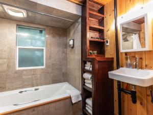 a bathroom with a tub and a sink and a mirror at Birdhouse Cottage in Glacier