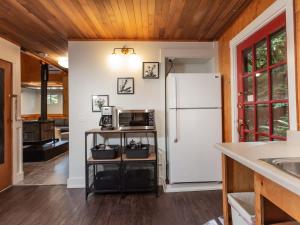 a kitchen with a white refrigerator and a sink at Birdhouse Cottage in Glacier +21 photos