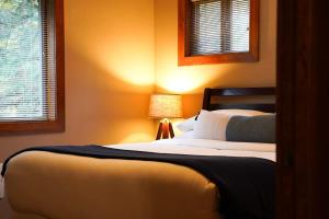 a bedroom with a bed with a lamp and two windows at Avventura Chalet in Glacier