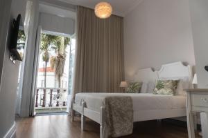 een witte slaapkamer met een bed en een balkon bij Casa das Palmeiras Charming House - Azores 1901 in Ponta Delgada
