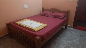 a bed with a wooden frame and purple sheets at Heera BEACH WAVE STAY in Gokarn