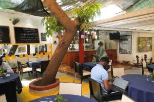 Ein Mann sitzt mit einem Laptop an einem Tisch in einem Restaurant in der Unterkunft Hôtel Oceanic in Dakar