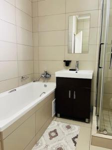 a bathroom with a tub and a sink and a mirror at CLASSY and COZY 3 in Fourways