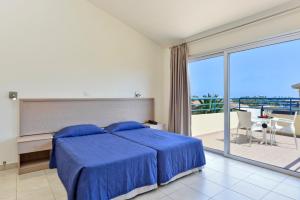 a bedroom with a blue bed and a balcony at Makronisos Village in Ayia Napa