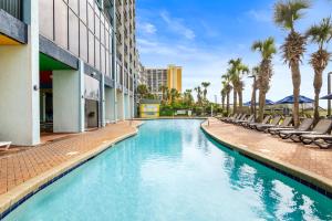 a swimming pool at a hotel with chairs and palm trees at Monterey Bay Suites in Myrtle Beach