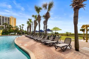a row of chairs next to a swimming pool with palm trees at Monterey Bay Suites in Myrtle Beach