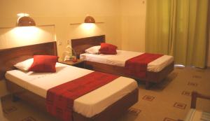 ein Hotelzimmer mit zwei Betten und roten Kissen in der Unterkunft Hôtel Oceanic in Dakar