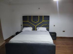 ein Schlafzimmer mit einem großen Bett mit gelb-schwarzem Kopfteil in der Unterkunft HattiHome in Freetown