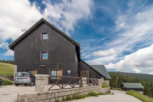 a black barn with a car parked in front of it at Rennerka Horská bouda in Strážné