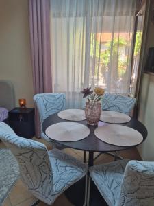 a table and chairs with plates and a vase on it at Ava Studio in Cisnădie
