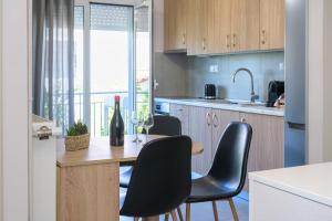 a kitchen with a table with chairs and a bottle of wine at Rania's Seaside Nest- Steps from the Beach in Kiaton