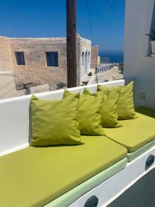 a bed with yellow pillows on top of a building at Finikas Cave House in Foinikiá