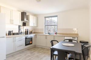 a kitchen with white cabinets and a table with chairs at Harbour View in Whitehaven