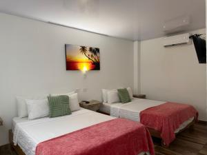 two beds in a room with a picture on the wall at Hotel Sunset Beach in Cartagena de Indias