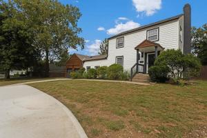 a white house with a yard and a driveway at Stylish KC FarmhouseHugeFencedYard in Merriam