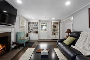 a living room with a black leather couch and a fireplace at Stylish KC FarmhouseHugeFencedYard in Merriam +55 photos