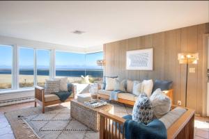 a living room with a couch and chairs and windows at Panoramic Water Views w Private Beach in Chatham