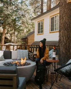 a woman sitting on a patio with a fire pit at Aery Pines in Wrightwood