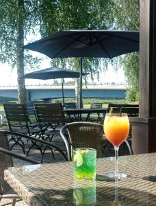 a glass of orange juice on a table with an umbrella at Rantakartano in Pori
