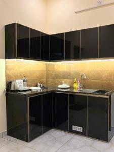 a kitchen with black cabinets and a sink at Uni Stay Inn in Cochin