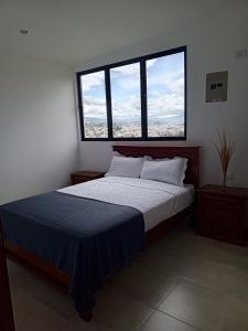 a bedroom with a large bed with two windows at Apartamentos Latacunga in Latacunga