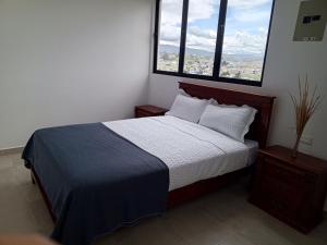 a bedroom with a bed and two windows at Apartamentos Latacunga in Latacunga