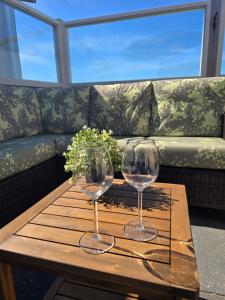 two wine glasses on a wooden table in front of a couch at PRACHTiG CHALET MEREL in Westerland