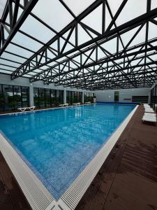 a large swimming pool with chairs in a building at Tropical Garden apart hotel in Batumi