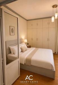 a bedroom with a large bed and a mirror at Akhet Cairo Suites in Cairo