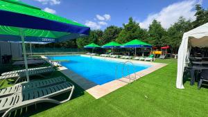 a swimming pool with chairs and umbrellas in a yard at Hotel Sucidava in Corabia