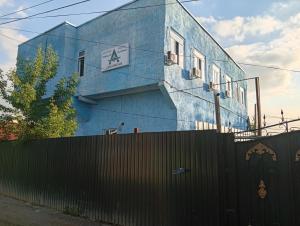 a blue building with a fence in front of it at Aerodrom Hotel - Hostel in Almaty