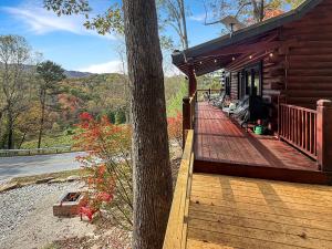 a wooden porch of a cabin with a tree at UnBearably Cozy - pool table, fire pit, central location in Bryson City