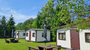 a group of camping cottages with a picnic table and an umbrella at Siedlisko Białogóra in Białogóra +12 photos