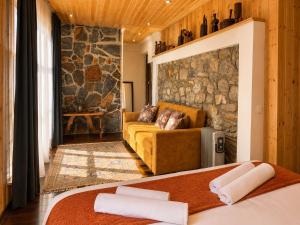 a bedroom with a couch and a stone wall at Guest House Keti Margiani Mestia in Mestia