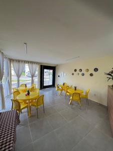 a dining room with yellow tables and yellow chairs at Pousada Mar de Pajuçara in Maceió