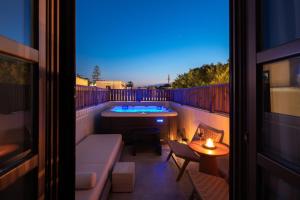 a balcony with a hot tub and a couch and a table at Karavel Suites - Old Town in Rhodes Town