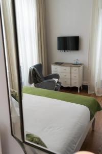 a bedroom with two beds and a desk and a television at Casa das Palmeiras Charming House - Azores 1901 in Ponta Delgada