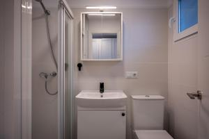 a white bathroom with a sink and a toilet at Acogedor studio a 10min de la playa in Torredembarra