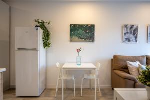 a kitchen with a white table and a white refrigerator at Acogedor studio a 10min de la playa in Torredembarra
