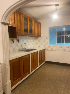 an empty kitchen with wooden cabinets and a sink at Los Aposentos Antigua in Antigua Guatemala +49 photos