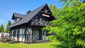 a black and white house with a tree at Siedlisko Białogóra in Białogóra