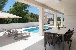 a patio with a table and chairs and a swimming pool at Villa DaEva in Drage