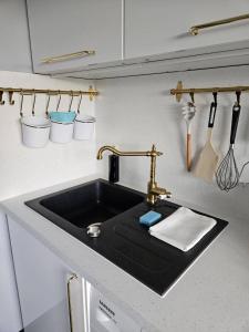 a kitchen sink with a black counter top at Royal View Apartment in Liepāja +44 photos