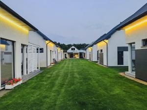 a long row of houses with a green yard at Morski Raj Apartamenty in Dębki