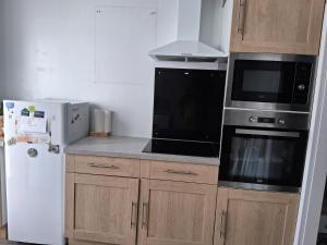 a kitchen with a microwave and a refrigerator at Maison proche bassin et océan in Arès +5 photos