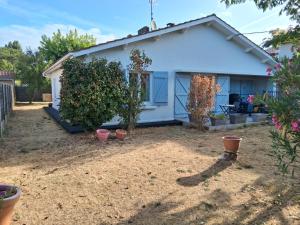 a small white house with plants in a yard at Maison proche bassin et océan in Arès