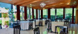 a dining room with tables and chairs and windows at Hotel Bardhi in Kuçovë
